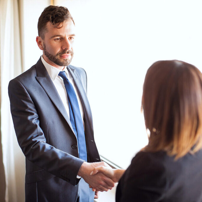 Portrait of an attractive young Hispanic business manager meeting and giving a handshake to a female client